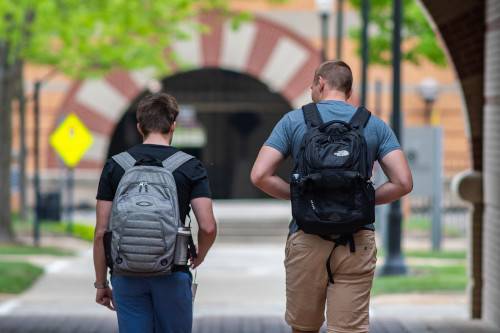 two students walking away from camera and wearing back packs